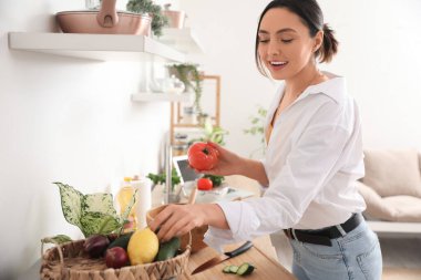 Mutfakta salata yapan taze domatesli genç bir kadın.