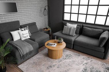Modern oturma odasının içinde rahat koltuklar, kanepe ve kahve masasının üzerinde floraryum var.