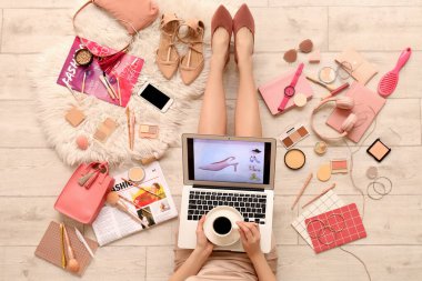 Dizüstü bilgisayarı olan bir kadın, bir fincan kahve ve aksesuar açık ahşap zeminden alışveriş yapıyor.