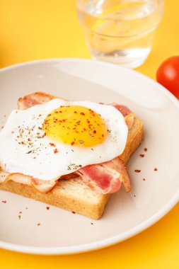 Sarı arka planda kızarmış yumurta ve pastırmalı lezzetli sandviç.
