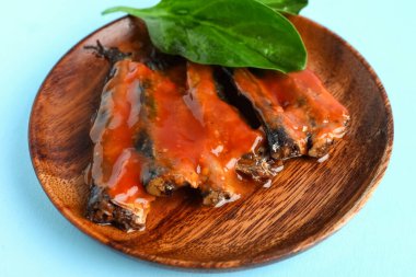 Domates soslu konserve balık tabağı ve mavi arka planda ıspanak yaprakları.