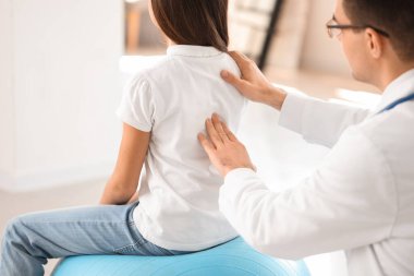 Doktor klinikteki küçük kızın duruşunu kontrol ediyor.