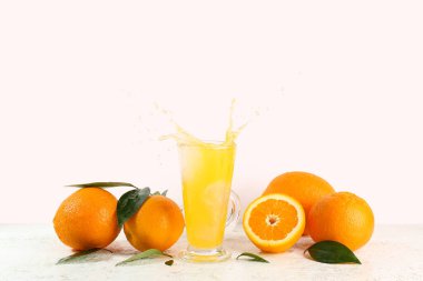 Bir bardak lezzetli portakal suyu ve beyaz arka planda taze meyveler.