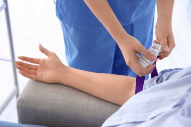 Genç bağışçıyı klinikte kan nakline hazırlayan hemşire, yakın plan.