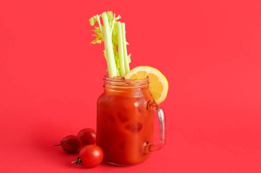 Kırmızı zemin üzerinde kereviz ve limon olan bir kavanoz Bloody Mary.