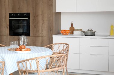 Modern mutfak, yemek masası ve beyaz tezgahlar.