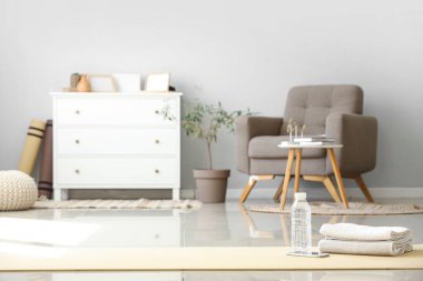 Oturma odasındaki jimnastik paspasının üstünde bir şişe su ve havluyla cep telefonu.