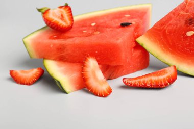 Gri arkaplanda taze karpuz ve çilek parçaları.