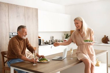 Olgun bir çift mutfakta yemek yiyor.