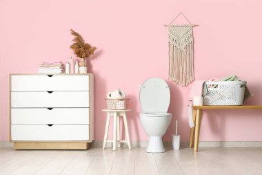 Seramik klozet ve kağıt rulolarla modern tuvaletin şık bir iç mekanı.