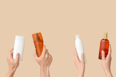 Bej arka planda güneş kremi şişeleri olan kadın elleri