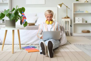 Yetişkin kadın yatak odasında İngilizce öğreniyor.