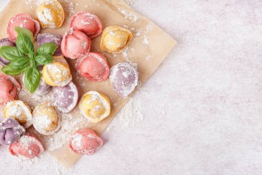 Renkli çiğ hamur köfteleri ve beyaz arka planda fesleğenli fırın kağıdı.