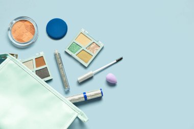 Mavi arka planda farklı dekoratif kozmetik ürünlere sahip çanta