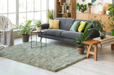 Rahat gri kanepe ve çiçeklerle aydınlık oturma odasının içinde.