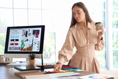 Ofiste çalışan bir fincan kahveyle kadın iç mimar.