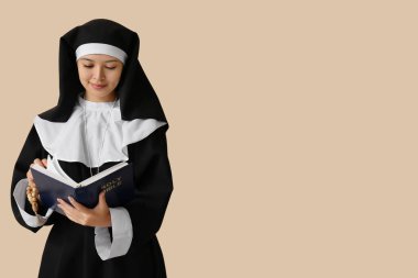 Bej arkaplanda İncil okuyan güzel Asyalı genç bir rahibe.