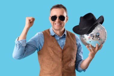 Mavi arka planda disko topu olan olgun bir kovboy.