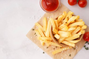 Beyaz arka planda ketçaplı bir kase lezzetli patates kızartması.