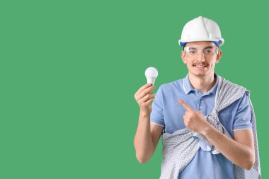 Yeşil arka planda ampulü gösteren erkek işçi