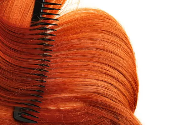 Beyaz arkaplanda taraklı kızıl saç, yakın plan.