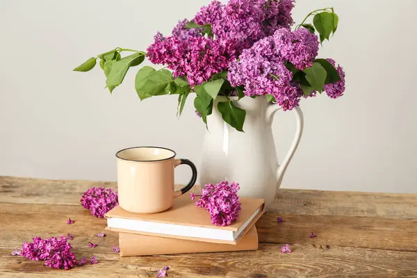 Sürahi güzel leylak çiçekleri, kahve ve kitaplarla beyaz duvarın yanındaki ahşap masada.