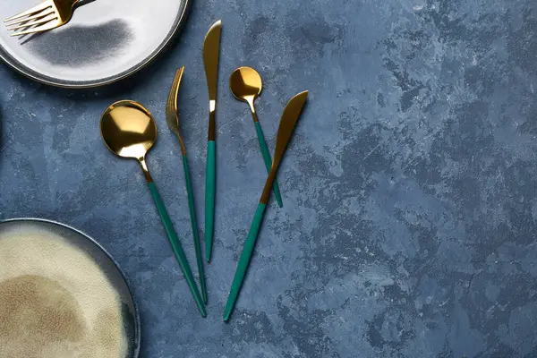 Mavi grunge masasında altın çatal bıçak seti, yakın plan.