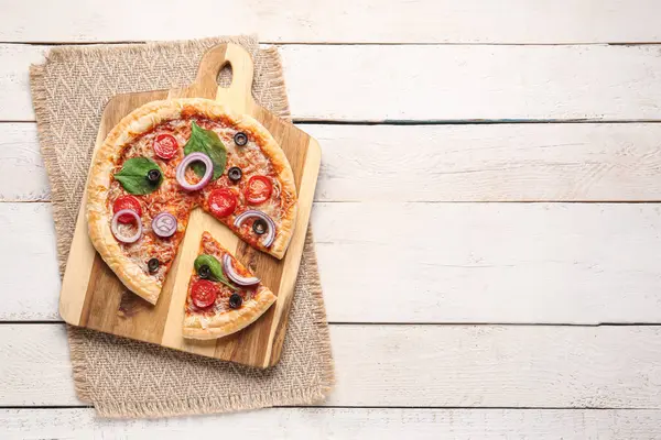 Beyaz ahşap arka planda fesleğenli ve domatesli lezzetli pizza.