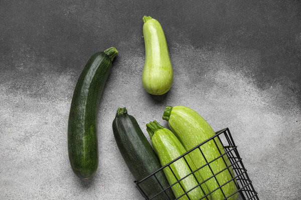 Basket with fresh green zucchini on grey background