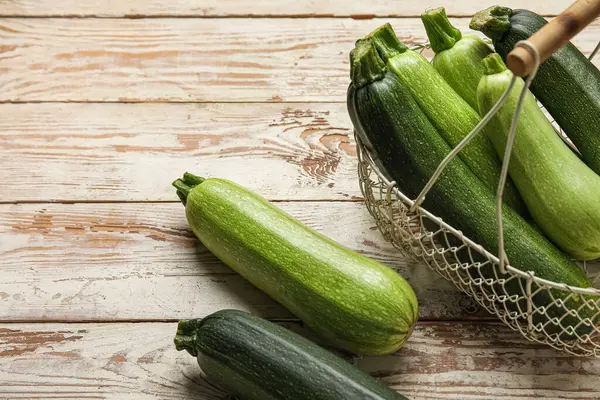 Beyaz ahşap arka planda yeşil kabaklı sepet.