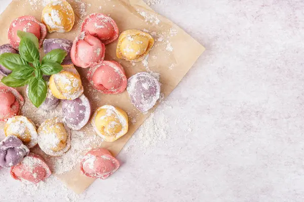 Renkli çiğ hamur köfteleri ve beyaz arka planda fesleğenli fırın kağıdı.