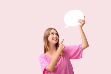 Güzel genç bir kadın pembe arka plandaki boş konuşma balonunu işaret ediyor.