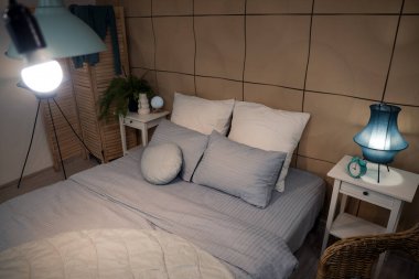 Parlayan lamba ve geceleri masaları olan şık bir yatak odası.