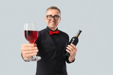 Hafif arka planda cam ve bir şişe kırmızı şarapla olgunlaşmış şarap garsonu, yakın plan.