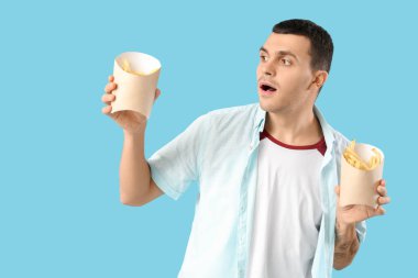 Mavi arka planda patates kızartması olan genç adam.