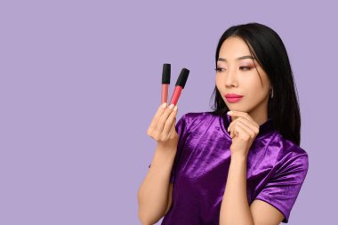 Güzel Asyalı kadın arkaplanda ruj seçiyor.