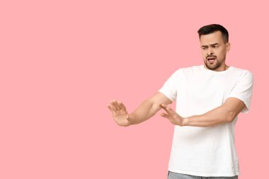 Pembe arka plandaki yakışıklı, endişeli genç adam.