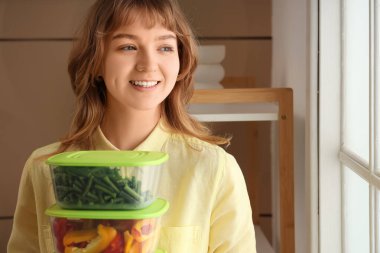 Evde donmak için elinde sebzelerle plastik kaplar tutan güzel genç bir kadın.