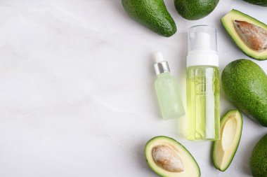 Taze avokadolar ve arka planda gerekli yağ şişeleri