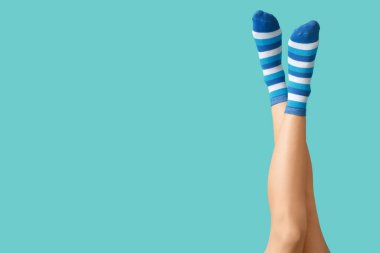 Mavi arka planda çizgili çoraplı genç kadın bacakları