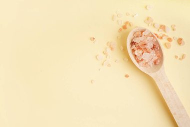 Tahta kaşık, Himalaya pembe tuzu ve sarı arka plan.