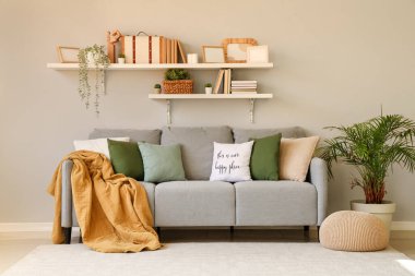 Gri duvarın yanında yastıkları olan rahat bir kanepe.