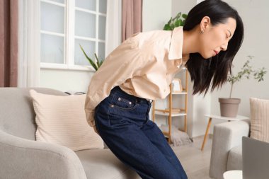 Evde hemoroit hastası genç bir Asyalı kadın.