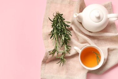 Çaydanlık ve bir fincan pembe arka planda sıcak biberiye çayı.