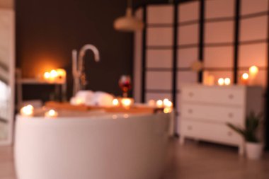 Şarap, havlu ve yanan mumlarla dolu bulanık bir küvet.