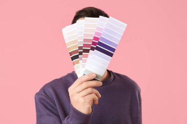 Pembe arka planda boya paletleri olan genç bir adam.