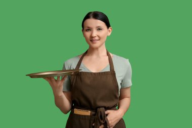 Yeşil arka planda tepsisi olan güzel bir garson kız.