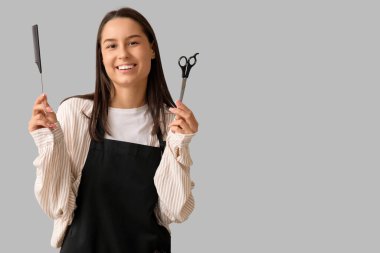 Taraklı ve makasla gri arka planda kadın kuaför