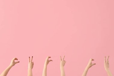 Pembe arka planda barış ve kalp jestleri gösteren kadın elleri