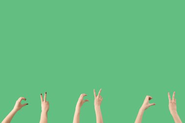 Yeşil arka planda barış ve kalp hareketleri gösteren kadın elleri